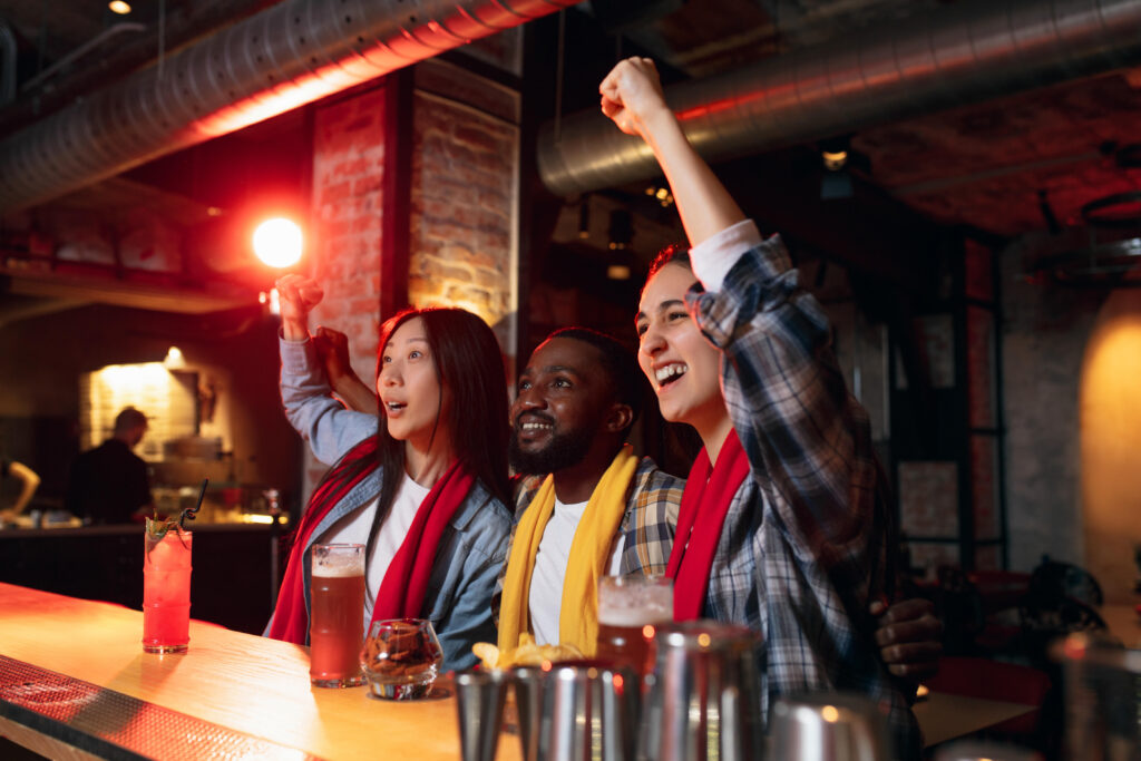 Glada vänner firar och ser på sport bartenderutbildning Stockholm