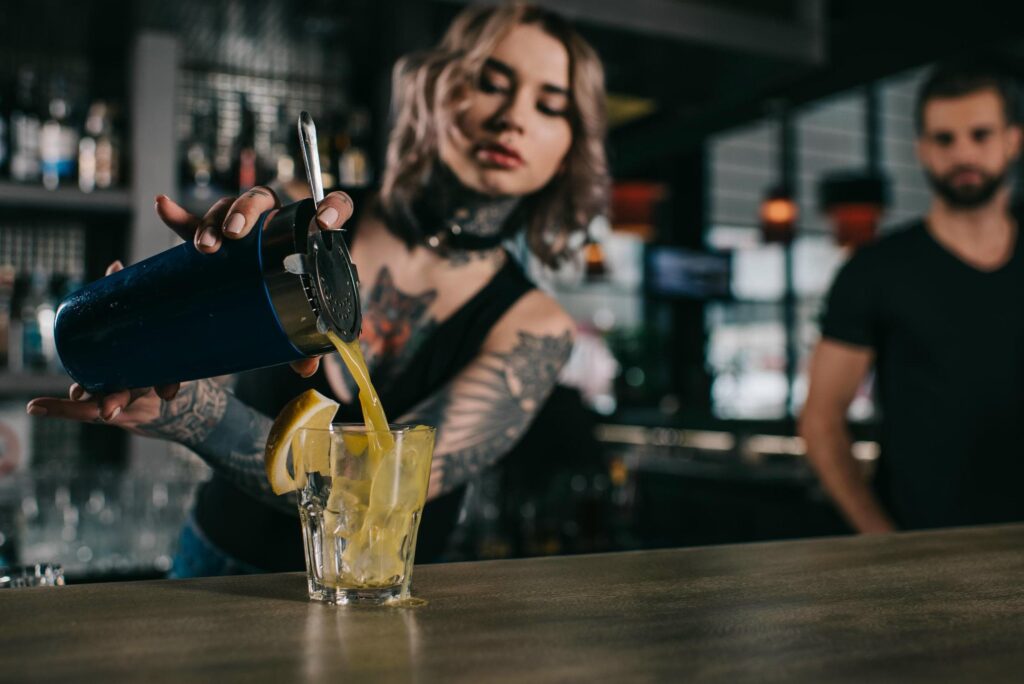 Tatuerad bartender förbereder drink under bartenderutbildning Stockholm