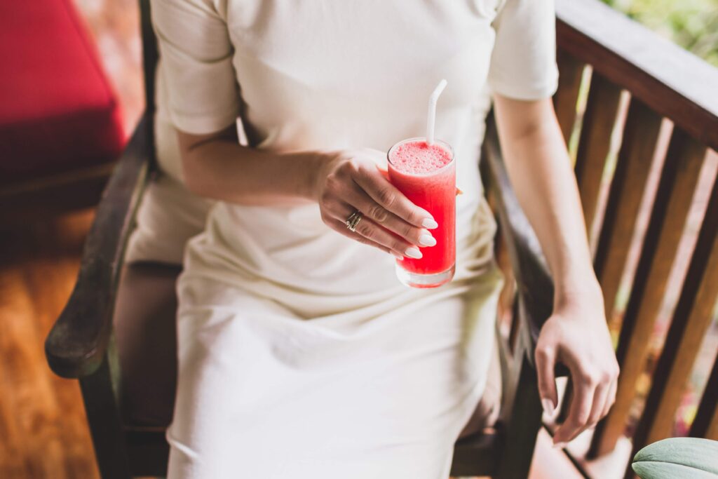 Kvinna håller ett glas med vattenmelondrink på sommar bröllop och möhippa