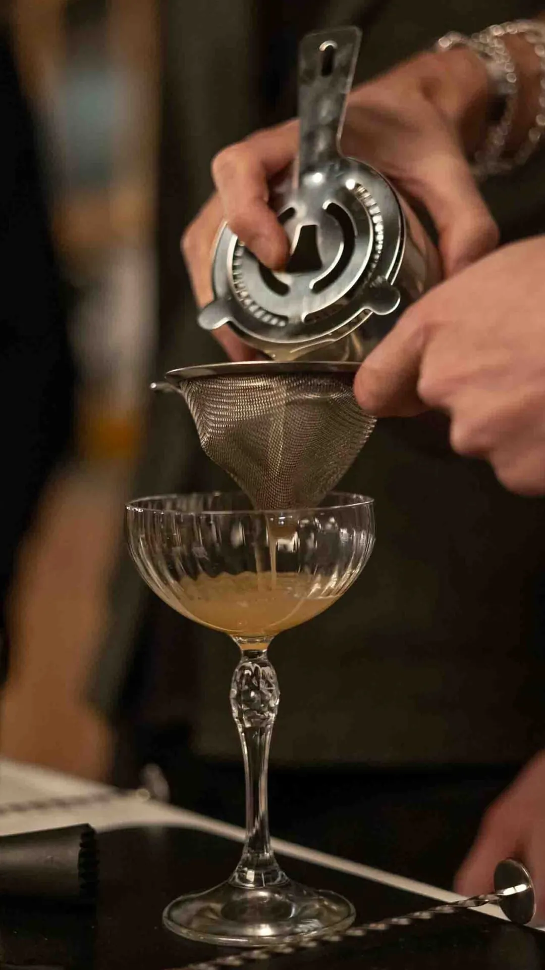 Bartender dubbelsilar en cocktail i ett coupeglas