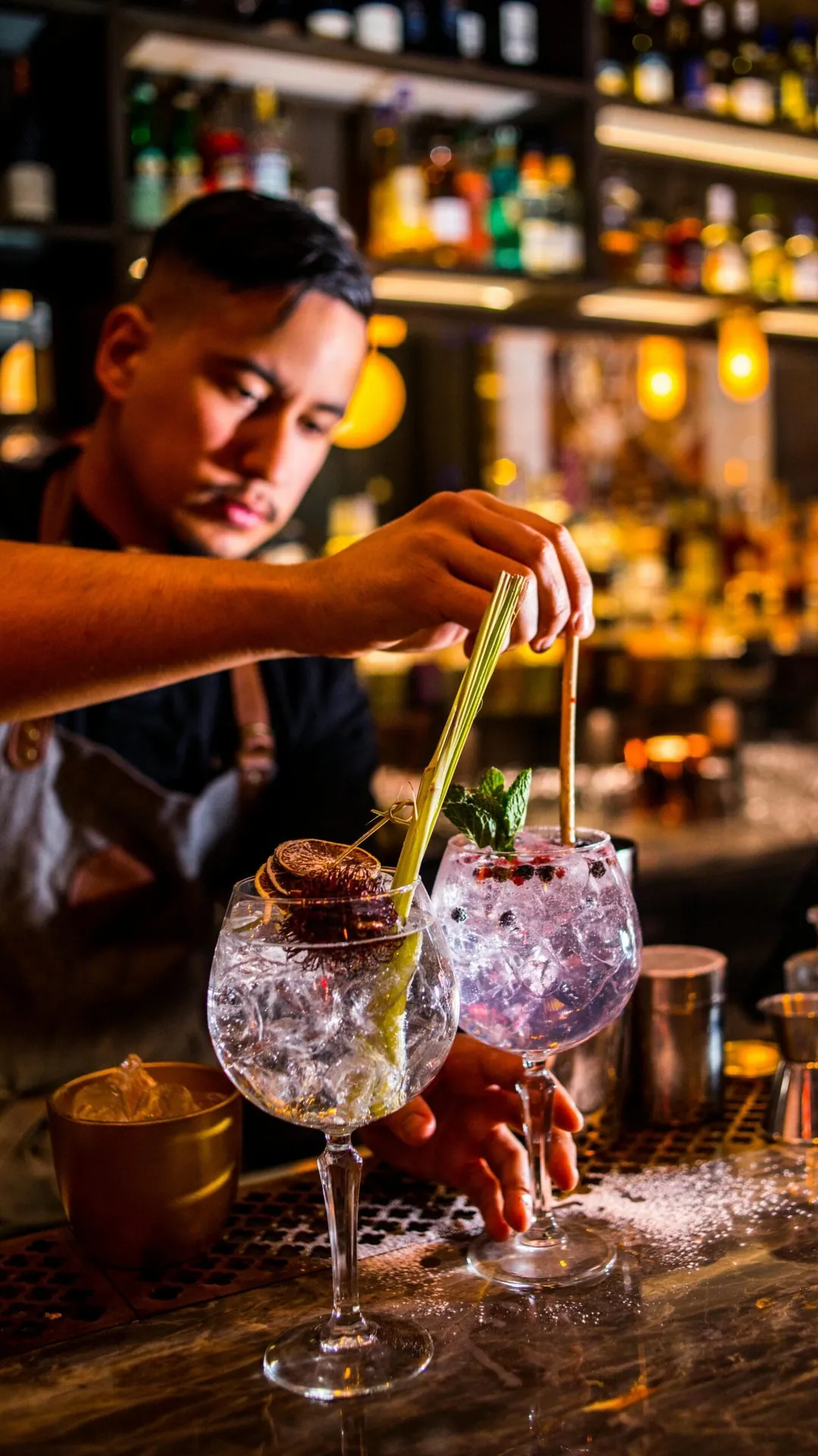 Bartender garnerar gin och tonic bakom baren
