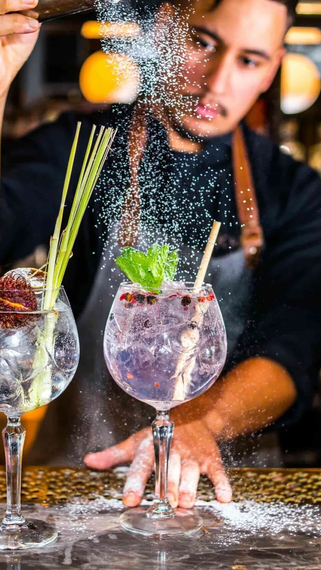 Bartender garnerar två gin och tonic vid baren