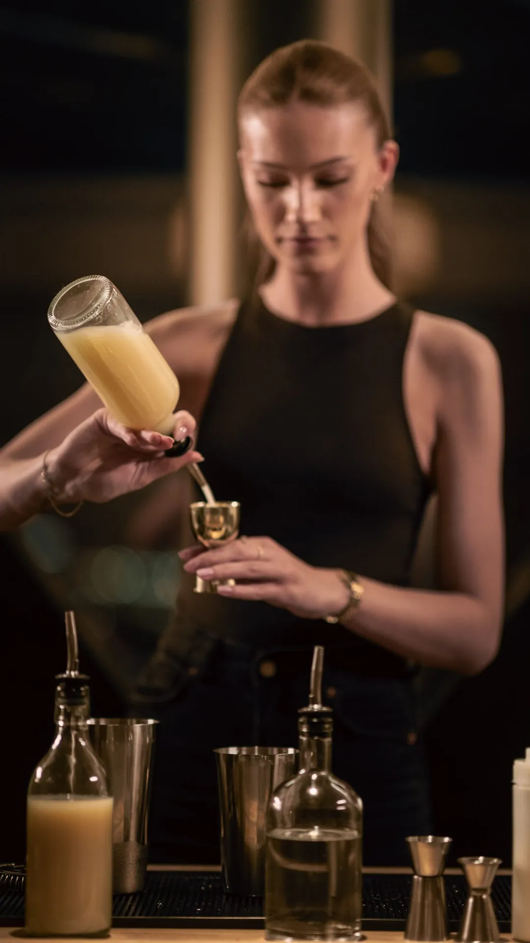 Bartender mäter upp juice med en jigger bakom baren