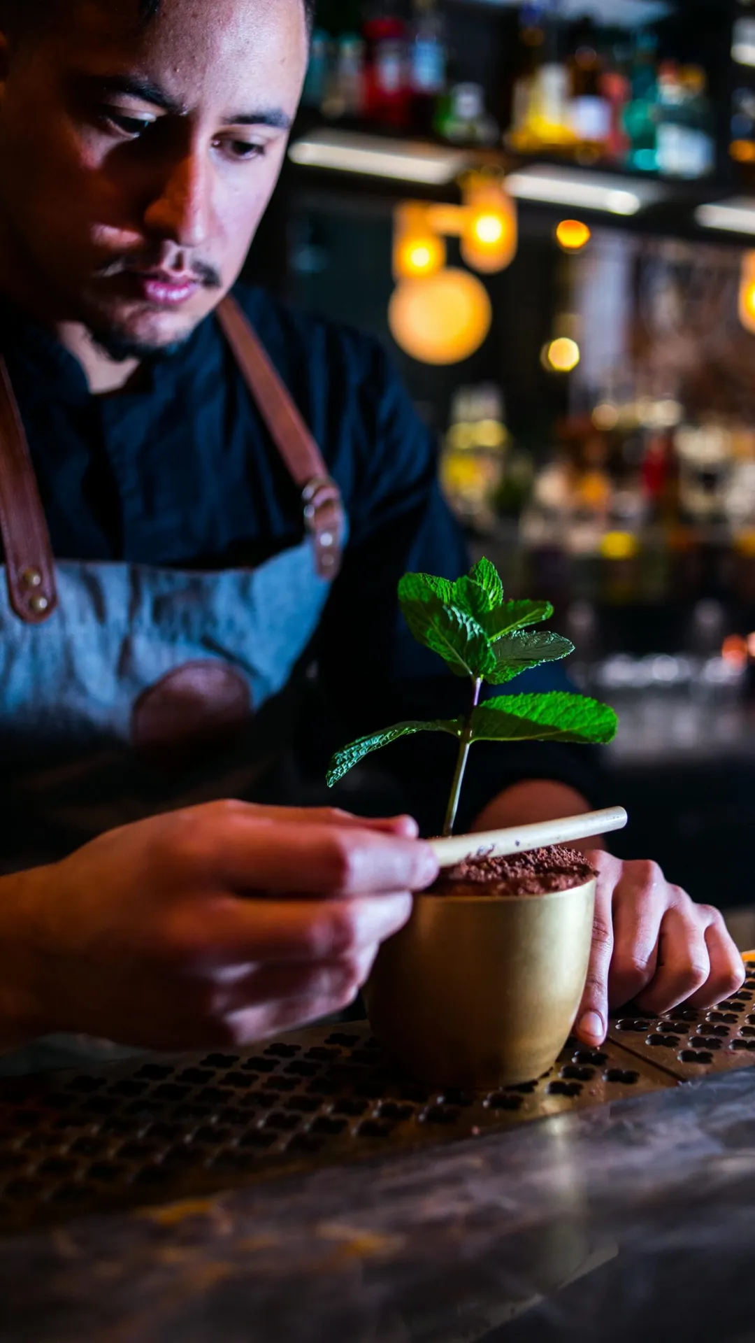 Bartender garnerar en drink med mynta vid baren
